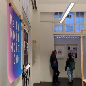 the MisCommunication poster shown in the foreground as visitors view art in the background