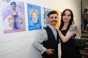 2 students posing in front of their colourful poster designs