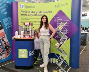 DGHE Stand at the East London Exhibition, Konstantina Diamantidi poses in front