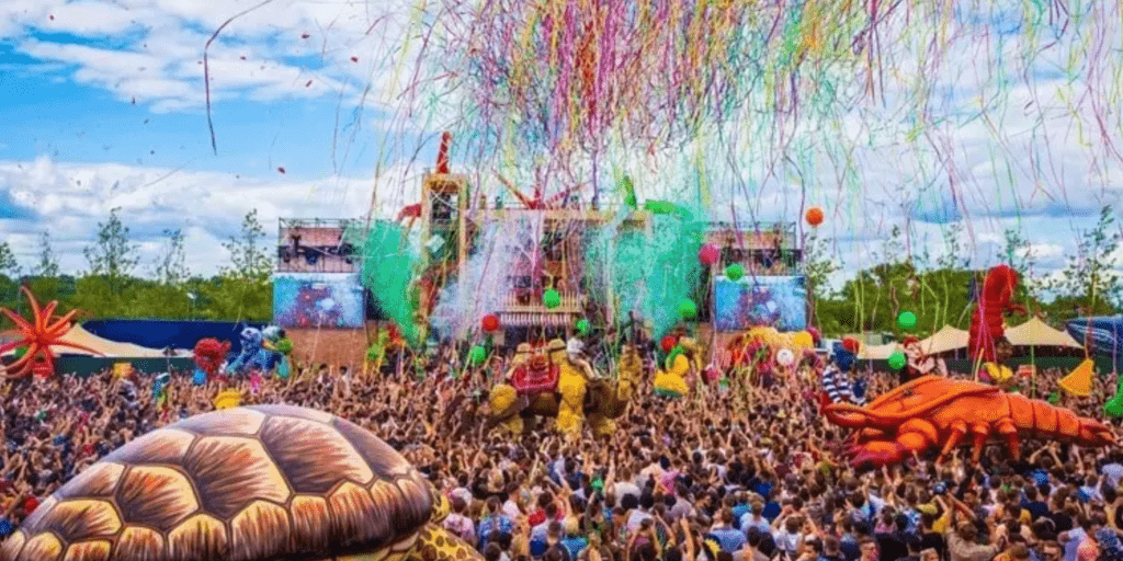 A photo of the Notting Hill Carnival showing the large group of people reunited before the stage. Bright colours and a party vibe dominate the picture.