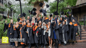 The Business Class of 2022 pose for a picture in their gowns. Some students lift their caps.