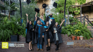 A group of Health & Social Care students throw their caps into the air in a classic graduation picture.