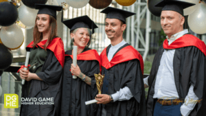 Four Art & Design students pose for a group photo. They all smile with their diplomas in hand.