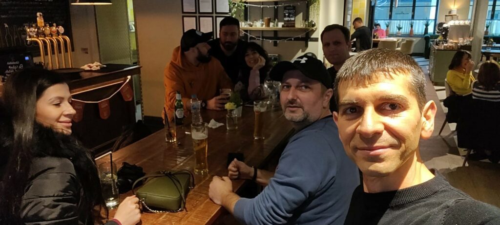 A group of students take a selfie in a crowded pub.