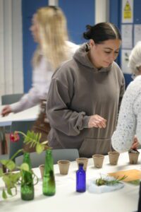 A student plants a herb with the help of Fiona