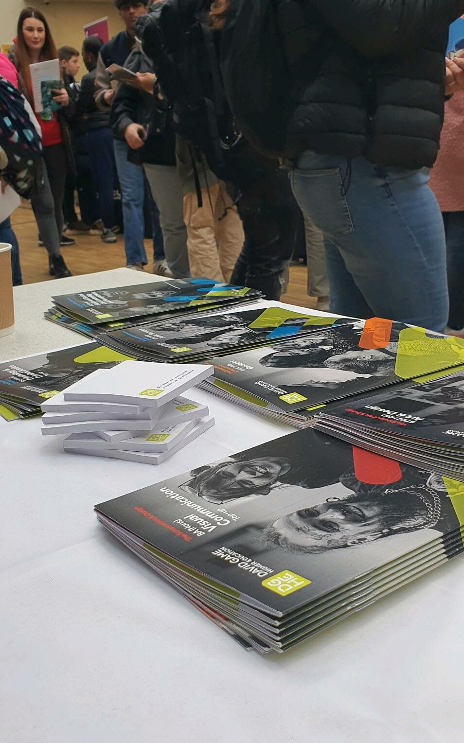 A table full of brochures can be seen in an University Fair