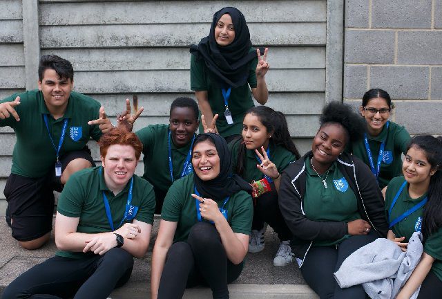 A picture of a group of MET Police volunteer cadets. Around nine young adults pose happily for the picture.