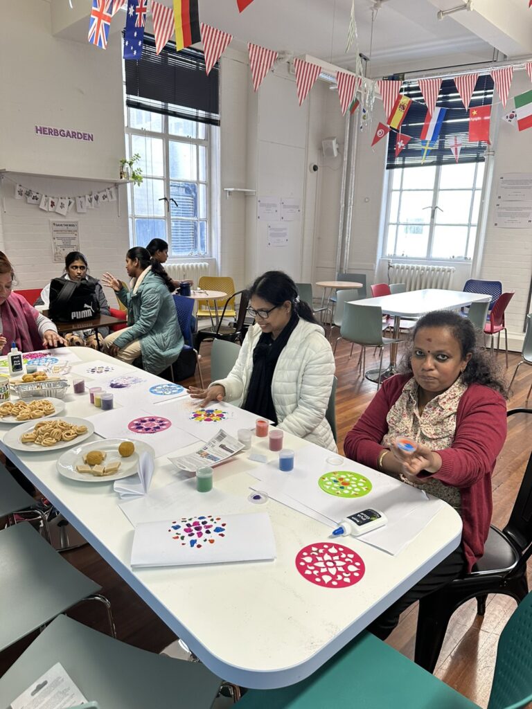 students sitting around the table and eating sweets while making Rangoli 