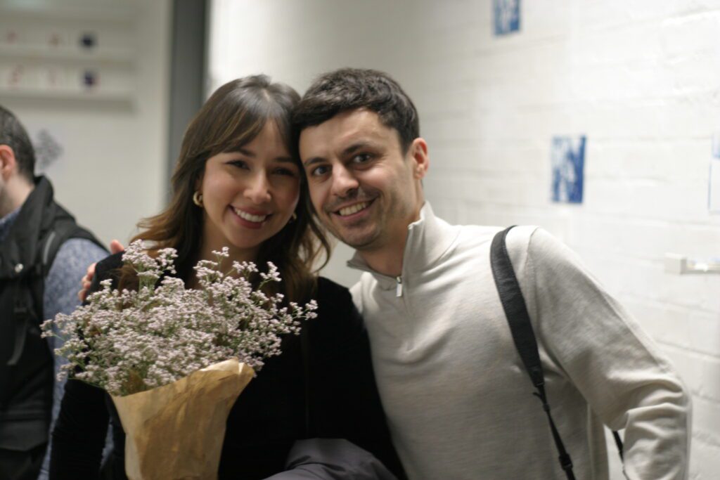 two students, one man and one woman, women holding flowers
